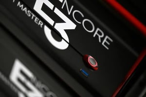 L'immagine ritrae un dettaglio del mixer grafico Barco Encore 3, in cui si intravede la scritta 'ENCORE E3', un tasto di accensione ed una porta USB 3